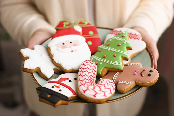 Χριστούγεννα μελόψωμο cookies στην πλάκα στα χέρια των γυναικών — Φωτογραφία Αρχείου
