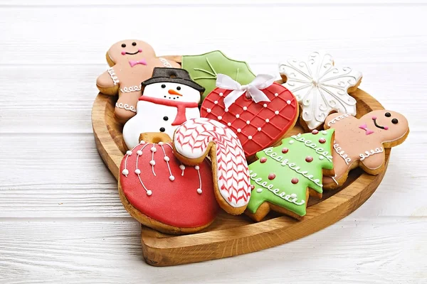 Различные типы рождественских декоративных пряников печенье на деревянной пластины в форме сердца на белом столе вид сверху, текстовое пространство — стоковое фото