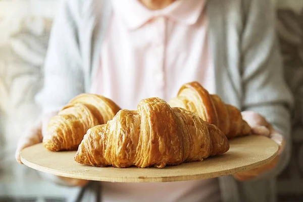 Elderly woman cooks french croissants, bare wrinkled hands, ingredients, soft warm morning light,top view