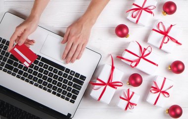 Kredi kartı ile eller. Ofis büro dizüstü bilgisayar ile kopya alanı ile Noel armağan beyaz arka plan düz üstünde yatıyordu. İş Noel tatil kavramı, tatil online alışveriş kavramı