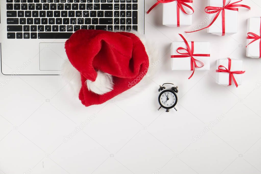 Office desk with laptop, christmas presents and wish list on white background flat lay with copy space. Business christmas holidays concept, holiday online shopping concept