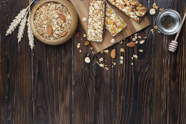 A trail mix bowl of dried fruit, raisins, cranberry with almonds, raisins, seeds, cashew, hazelnut nuts with honey. Vegetarian fitness energy bar snacks. Close up, top view, copy space, background.