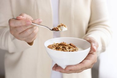 Ev yapımı granola karışık Kuruyemiş, yulaf ve Yunan yoğurt ile kahvaltılık kase yemek kadın. Erkek kaju fıstığı, badem, fındık ile sağlıklı vejetaryen superfood tutan eller. Gün ışığına, yakın çekim
