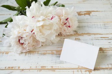 İhale ve yumuşak beyaz peonies çizilmiş ahşap dokulu masa üzerinde.