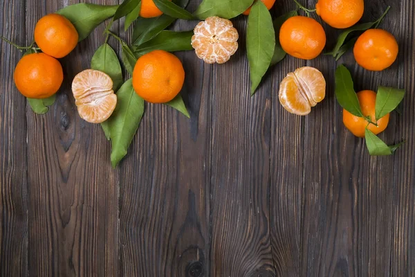 Verse tangerine sinaasappelen op een houten tafel. Gepelde mandarijn. Helften, segmenten en hele clementines closeup. — Stockfoto