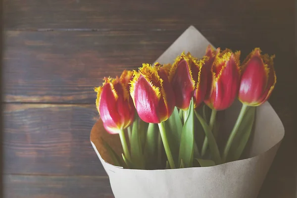 Stilvolle Vintage-Bouquet-Komposition mit zweifarbigen Tulpen auf dunkelbraunem Holztisch. Zweifarbige Blumen in Papier gewickelt. — Stockfoto