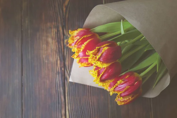 Élégante composition de bouquet vintage avec des tulipes bicolores sur une table en bois brun foncé. Fleurs bicolores enveloppées dans du papier . — Photo