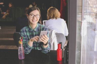Kapuçino, latte, macchiato, çay içme, tablet bilgisayar kullanarak ve bir kafe / bar telefonda konuşmak mutlu genç kadın.