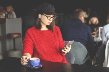 Kapuçino, latte, macchiato, çay içme, tablet bilgisayar kullanarak ve bir kafe / bar telefonda konuşmak mutlu genç kadın.