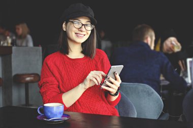 Kapuçino, latte, macchiato, çay içme, tablet bilgisayar kullanarak ve bir kafe / bar telefonda konuşmak mutlu genç kadın.