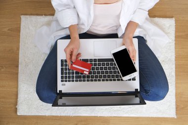 «Ana sayfa» internet'te sörf, online alışveriş dizüstü bilgisayar ve cep telefonu, borç bekletme öğrenci kız görünümünü / kredi kartı, promosyon kodu girme. Ek yükü genç kadın Tur, kot pantolon beyaz gömlek, ahşap dokulu zemin.