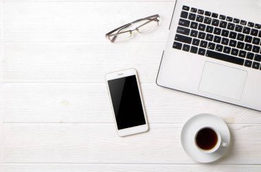 Blogger / işadamı / işkadını, bu dizüstü bilgisayar, boş ekran smartphone, kahve fincanı ve malzemeleri ile uzman'ın beyaz ahşap ofis alanı tablo. Üstten Görünüm, kopya alanı, düz lay, Tepegöz, zemin.