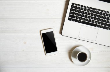 Blogger / işadamı / işkadını, bu dizüstü bilgisayar, boş ekran smartphone, kahve fincanı ve malzemeleri ile uzman'ın beyaz ahşap ofis alanı tablo. Üstten Görünüm, kopya alanı, düz lay, Tepegöz, zemin.