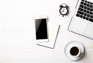 Blogger / işadamı / işkadını, bu dizüstü bilgisayar, boş ekran smartphone, kahve fincanı ve malzemeleri ile uzman'ın beyaz ahşap ofis alanı tablo. Üstten Görünüm, kopya alanı, düz lay, Tepegöz, zemin.