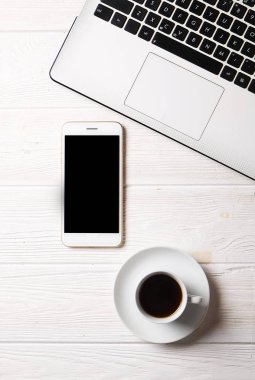 Blogger / işadamı / işkadını, bu dizüstü bilgisayar, boş ekran smartphone, kahve fincanı ve malzemeleri ile uzman'ın beyaz ahşap ofis alanı tablo. Üstten Görünüm, kopya alanı, düz lay, Tepegöz, zemin.