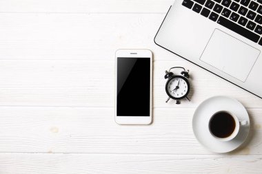 Blogger / işadamı / işkadını, bu dizüstü bilgisayar, boş ekran smartphone, kahve fincanı ve malzemeleri ile uzman'ın beyaz ahşap ofis alanı tablo. Üstten Görünüm, kopya alanı, düz lay, Tepegöz, zemin.