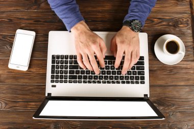 Raslantı giyimli öğrenci / blogger / yazar / man pc dizüstü bilgisayarda çalışan, klavyede yazarak, içme kafe / bar, smartphone kullanarak blog makale yazma. Çalışma alanı Ofis Masası Üstten Görünüm.