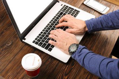 Raslantı giyimli öğrenci / blogger / yazar / man pc dizüstü bilgisayarda çalışan, klavyede yazarak, içme kafe / bar, smartphone kullanarak blog makale yazma. Çalışma alanı Ofis Masası Üstten Görünüm.
