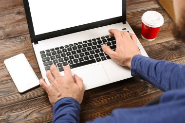 Raslantı giyimli öğrenci / blogger / yazar / man pc dizüstü bilgisayarda çalışan, klavyede yazarak, içme kafe / bar, smartphone kullanarak blog makale yazma. Çalışma alanı Ofis Masası Üstten Görünüm.