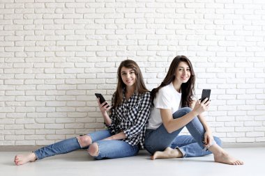 Mutlu bin yıllık kızlar içeride eğleniyor. Mükemmel karizmatik gülümsüyor, kahverengi gözleri, dalgalı siyah saçlı genç güzel kadınlarla. Minimalist iç, beyaz tuğla duvar arka plan, loft tarzı dokulu..