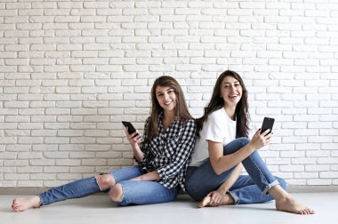 Mutlu bin yıllık kızlar içeride eğleniyor. Mükemmel karizmatik gülümsüyor, kahverengi gözleri, dalgalı siyah saçlı genç güzel kadınlarla. Minimalist iç, beyaz tuğla duvar arka plan, loft tarzı dokulu..