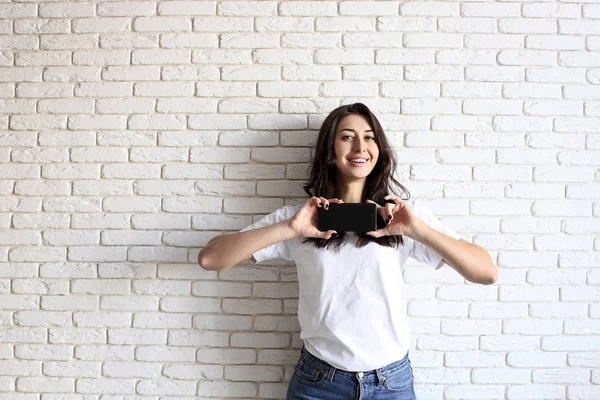 Menina milenar feliz se divertindo dentro de casa. Retrato de mulher jovem com diastema gap entre os dentes. Belo sorriso. Interior minimalista, tijolo branco texturizado fundo da parede, estilo loft. Espaço de cópia . — Fotografia de Stock