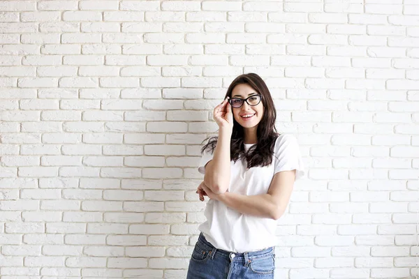 Happy millennial girl having fun indoors. Portrait of young woman with diastema gap between teeth. Beautiful smile. Minimalistic interior, white brick textured wall background, loft style. Copy space. — Stock Photo, Image