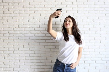 Şık kadın selfie alışveriş çantası ile üzerinde sarı duvar arka plan yapma. Kış tatil satış