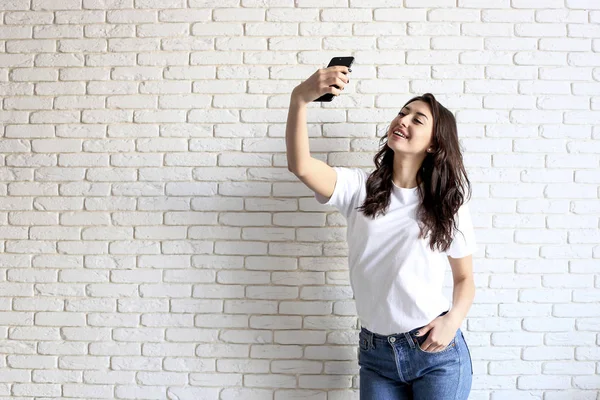 Stylische Frau macht Selfie mit Einkaufstasche auf gelbem Wandhintergrund. Winterschlussverkauf — Stockfoto