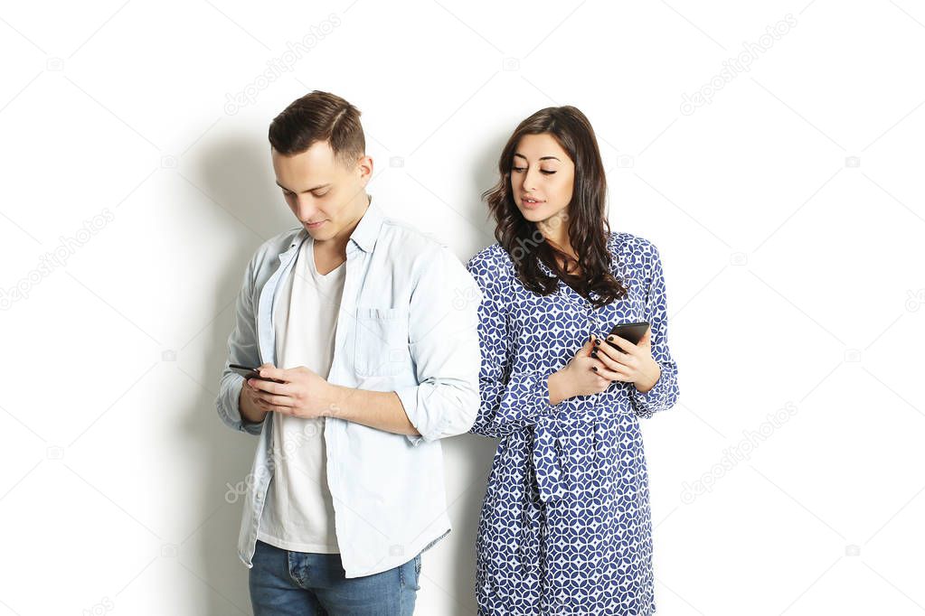 Jealous wife spying her husband mobile phone while he is reading a message. Technology & relationship concept. Modern romance troubles. Male and female online dating app. Swiping, browsing, surfing