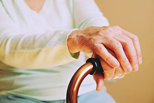 Mujer madura en un centro de atención de ancianos recibe ayuda de personal de enfermería del hospital. Primer plano de las manos arrugadas y envejecidas de una mujer mayor. Abuela vida cotidiana . — Foto de Stock