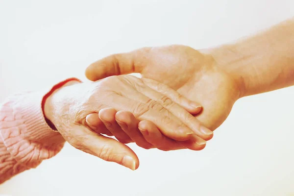 Mogen kvinna äldre vård anläggning får hjälp från sjukhus personal sjuksköterska. Närbild av åldern rynkiga händer av senior kvinna. Grand mor vardagen. — Stockfoto