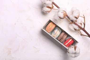 Geleneksel Fransız badem karamelli çikolata kızılcık macarons tatlı bisküvi tepside beyaz gri beton dokulu arka plan masa üstü. Lezzetli ama sağlıksız gıda.