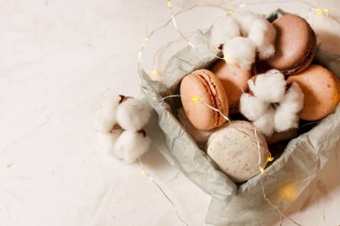 Geleneksel Fransız badem karamelli çikolata kızılcık macarons tatlı bisküvi tepside beyaz gri beton dokulu arka plan masa üstü. Lezzetli ama sağlıksız gıda.