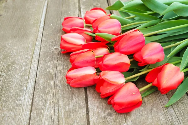 Reihe leuchtend roter Tulpenblüten am Stiel. Holzhintergrund mit Scopy-Textfläche. Willkommen im Frühling und Sommer. Muttertags-Hintergrund, internationaler Frauentag-Gruß. Draufsicht, flache Lage. — Stockfoto