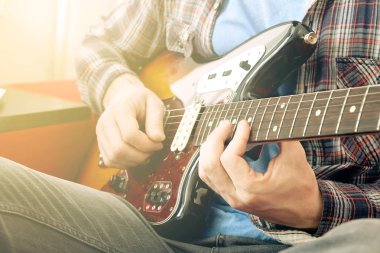 Raslantı genç adam gitar şarkıları evde odada ile giyinmiş. Online gitar dersleri kavramı. Erkek gitarist pratik akor kulpları.