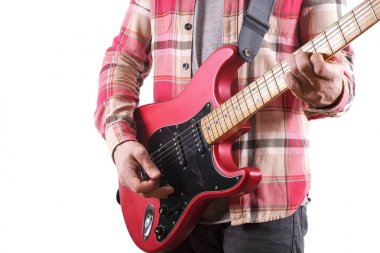 Raslantı genç adam gitar üzerinde beyaz izole şarkıları çalma ile giyinmiş. Masa üstünde laptop. Online gitar dersleri kavramı. Erkek gitarist pratik akor kulpları.
