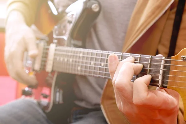 Nonchalant klädd ung man med gitarr som spelar låtar i rummet hemma. Online gitarr lektioner koncept. Manliga gitarrist praktiserande ackord grepp. — Stockfoto