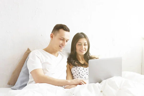 Young couple watching tv show, reading a message. Technology & relationship concept. Modern romance troubles. Male & female online dating app. Laptop, chatting, shopping, browsing, surfing.