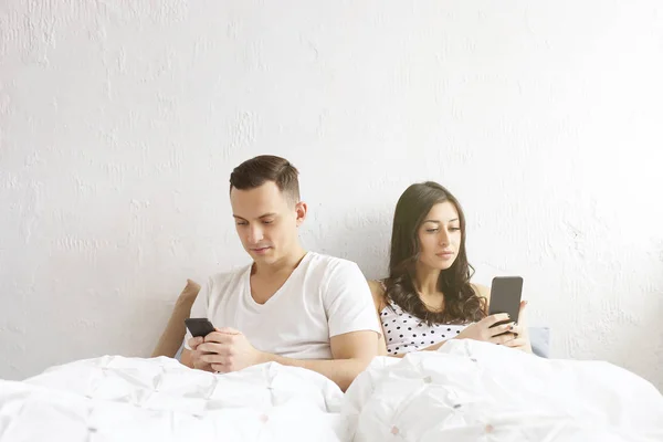 Young couple checking mobile phone, reading a message. Technology & relationship concept. Modern romance troubles. Male & female online dating app. Touch screen, chatting, swiping, browsing, surfing.