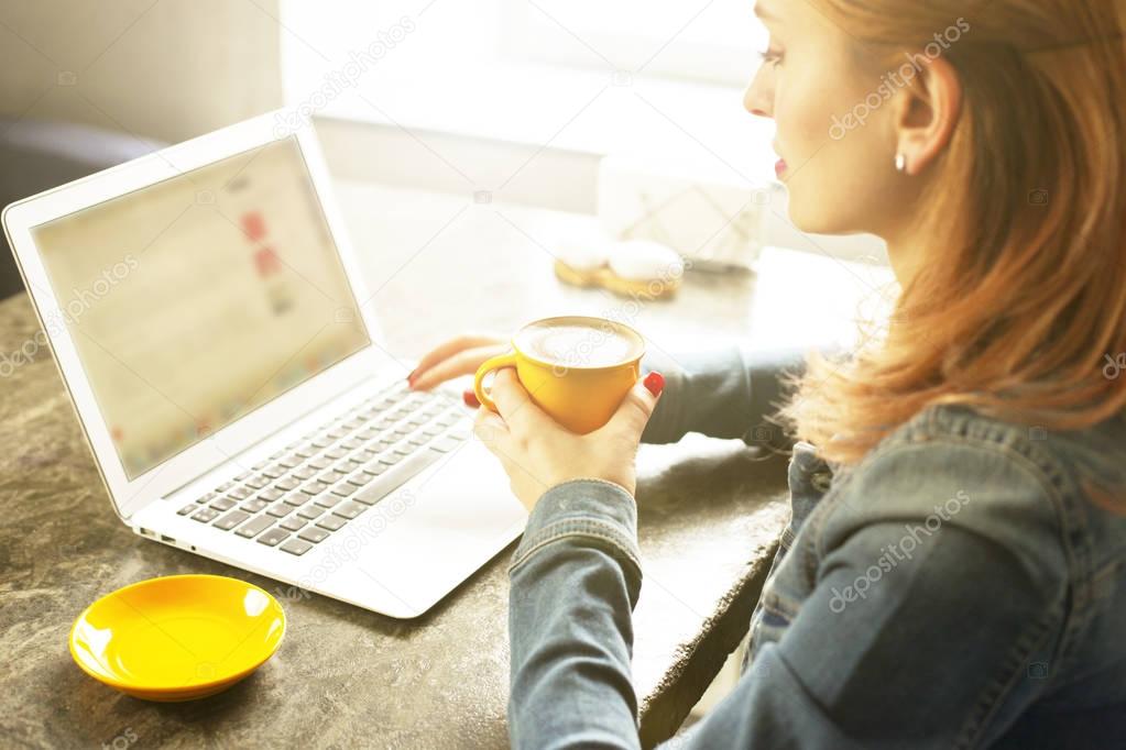 Attractive hipster young woman in modern loft cafe coffee shop restaurant. Writer, blogger, designer, freelancer, remote work process. E-shopping, online shopping, m-shopping.