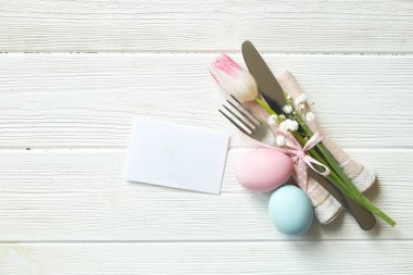 Paskalya tablo randevular, Tablo ayarı seçenekleri döşeme. Gümüş sofra öğeleri şenlikli dekorasyonu ile. Çatal, bıçak ve çiçekler. Mutlu Paskalya tatili.