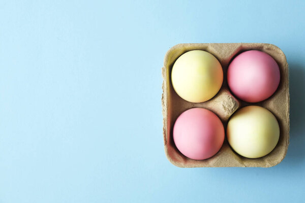 Пасхальные яйца разного цвета откладываются и укладываются в красивую композицию с белыми полевыми цветами. Открытка с пробелом в тексте
.