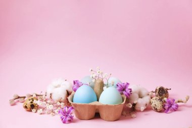 Hasır sepet saman ve dekoratif çiçekler organik yumurta geleneksel Paskalya kartı şablonu pastel renklerle boyalı.