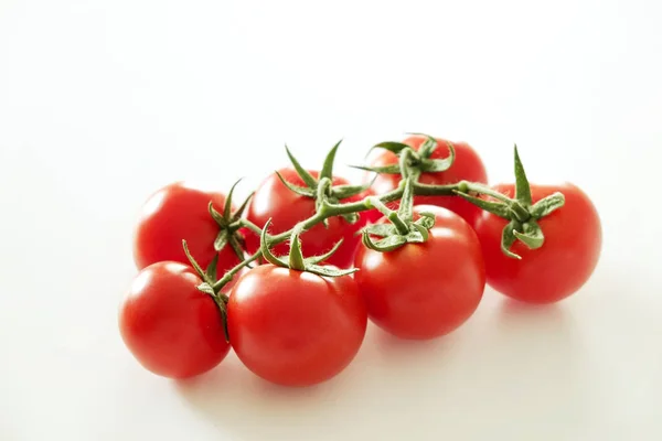 Composição de leigos planos minimalistas de tomates cereja vermelho brilhante refletindo a luz, colocando no topo da mesa branca sólida . — Fotografia de Stock