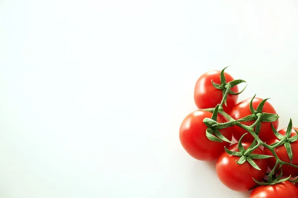 Composição de leigos planos minimalistas de tomates cereja vermelho brilhante refletindo a luz, colocando no topo da mesa branca sólida . — Fotografia de Stock