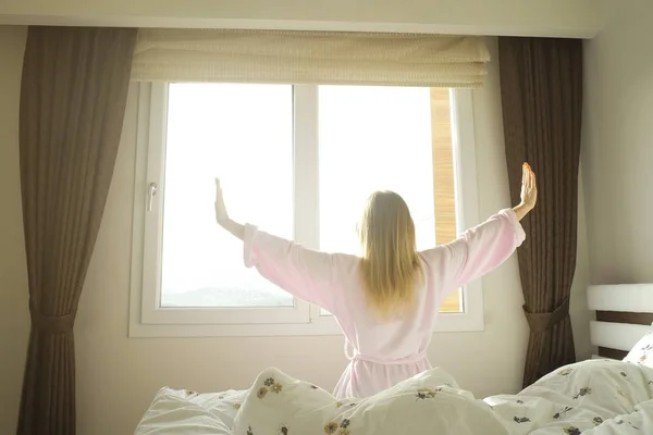Hotellrommet er fullt av sollys og solstråler. Optimistisk start på dagen. Blond kvinne koser seg hjemme med morgendagslys. Ny dag nytt meg-konsept . – stockfoto
