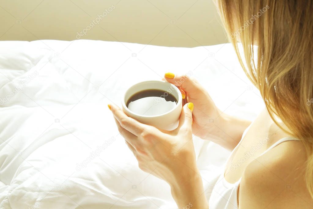 Big spacey hotel room full of sunlight and sun beams. Optimistic start of the day. Blond woman cozy home clothing welcoming the morning daylight. New day new me concept.
