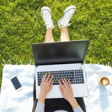 Onun dizüstü bilgisayarda ödev yeşil çim üzerinde oturan Üniversite öğrenci kız. Makale, eshopping, sosyal ağ üstünde onun pc defter yazma genç kadın park bloglama oturuyordu. kopya alanı.