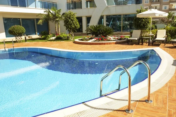 Área de piscina de novo complexo residencial de luxo com azulejos, alças de escadas cromadas e drenos. Dia lindo ensolarado . — Fotografia de Stock